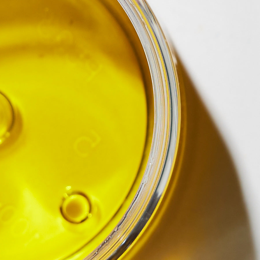 Close up view of a golden oil in a glass jar.