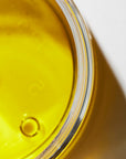 Close up view of a golden oil in a glass jar.