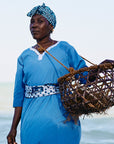 A Mwani Zanzibar team member wearing blue garment in front of the ocean.