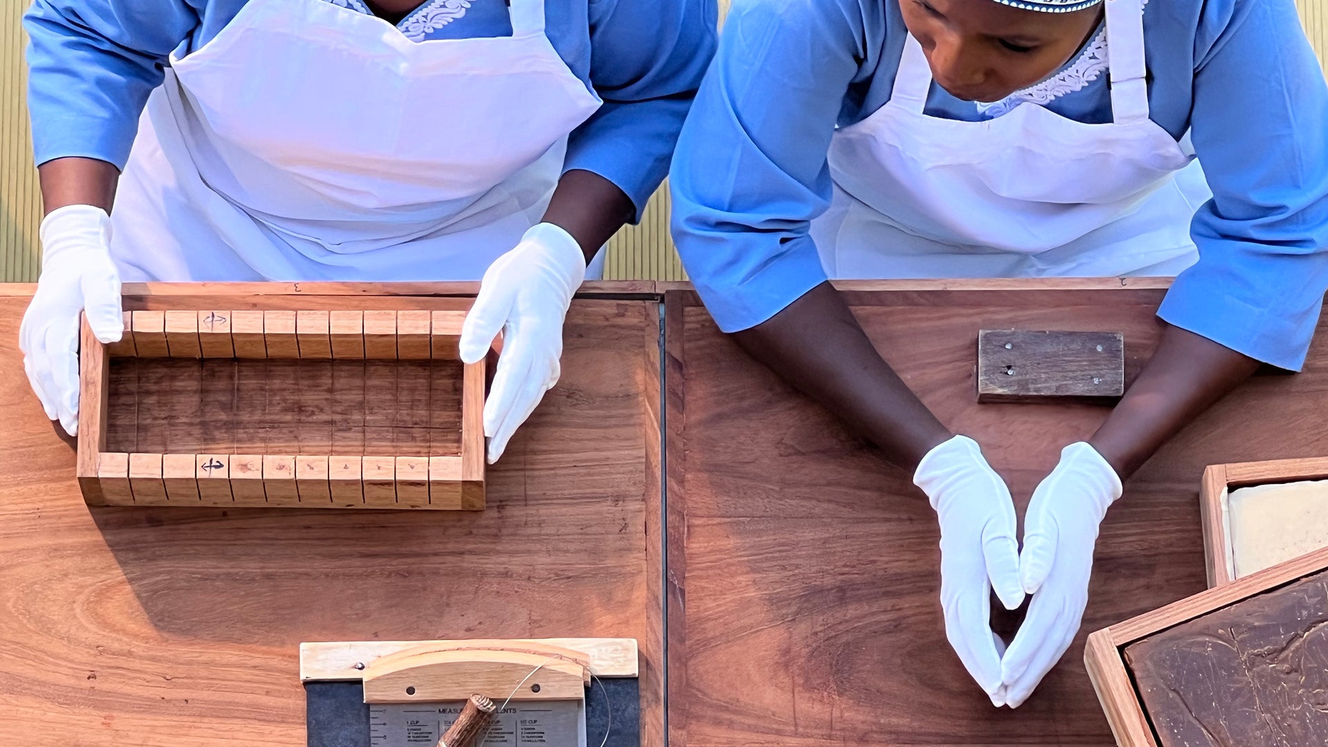 Overhead view of Mwani Zanzibar Mamas preparing soap bars at table.