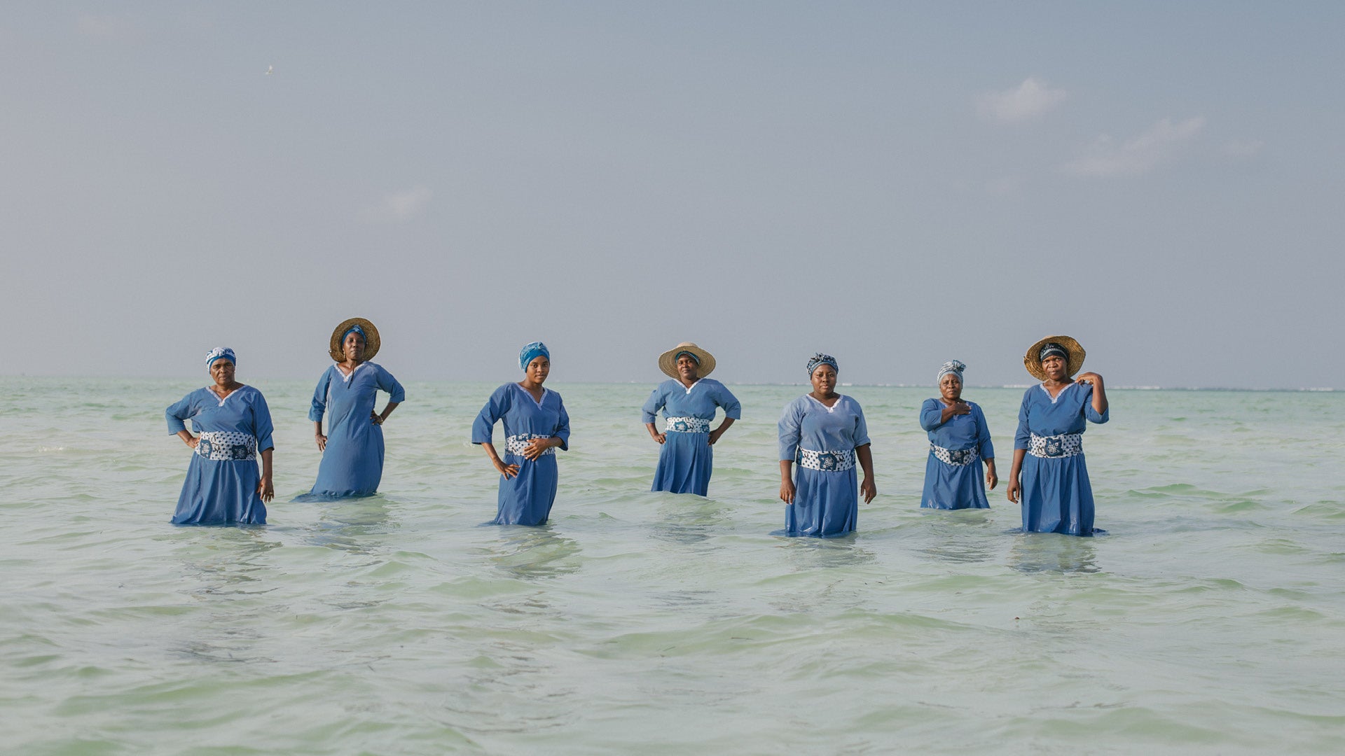 4 Mwani Zanzibar Mamas standing in the Indian Ocean during daytime.